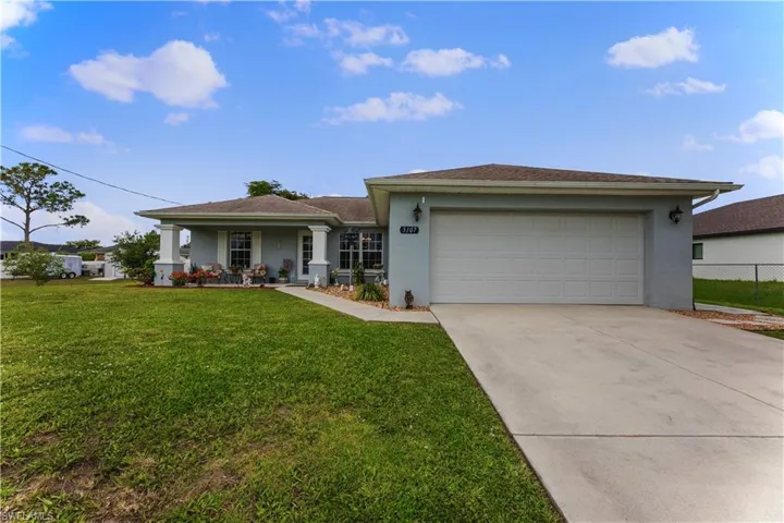 Ranch-style home featuring a garage and a front lawn