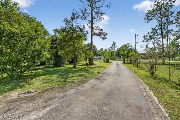 View of asphalt driveway featuring a gated entry and lots of guest parking