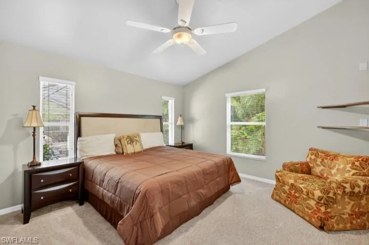 Carpeted King Size Primary Bedroom featuring lofted ceiling and a ceiling fan