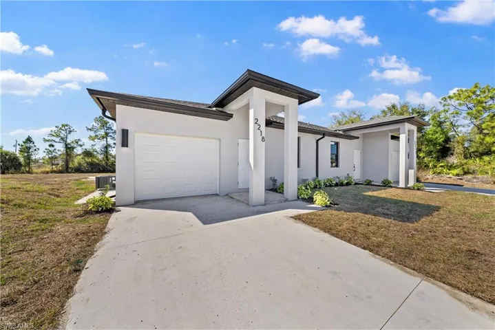 View of front facade with an attached garage, stucco siding, concrete driveway, and a front yard