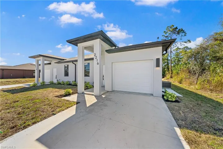 View of front of property with a garage, stucco siding, a front lawn, and concrete driveway
