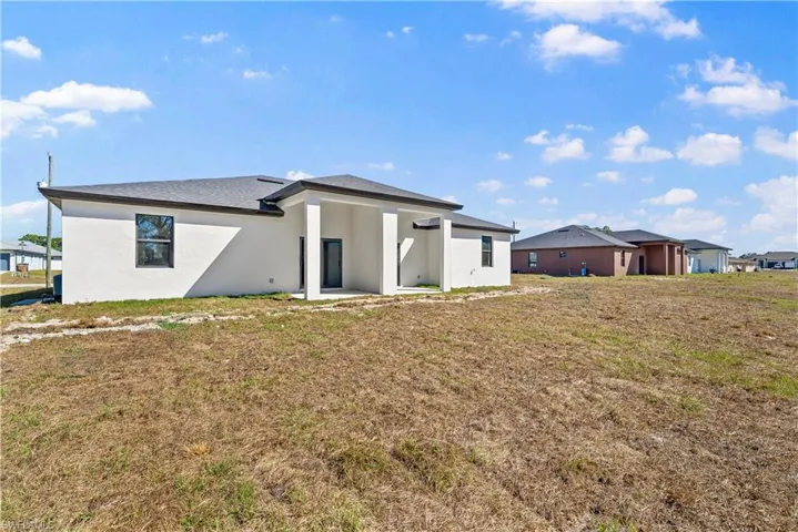 Rear view of property with stucco siding and a lawn