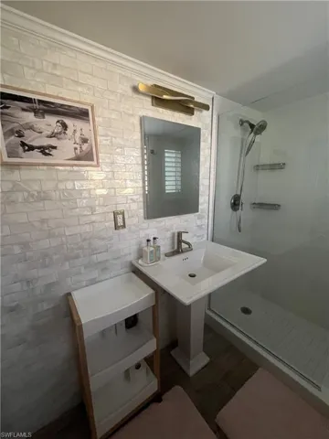 Bathroom featuring white subway tile walling, a pedestal sink with a bronze-finish faucet, and a glass-enclosed shower with a rainfall showerhead