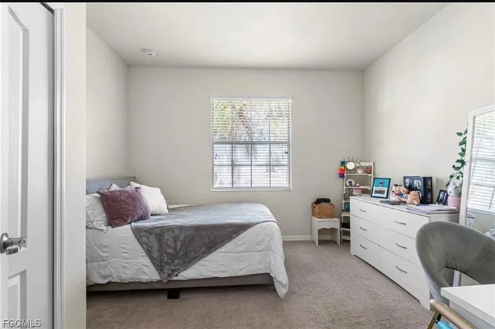 Bedroom featuring light carpet and baseboards