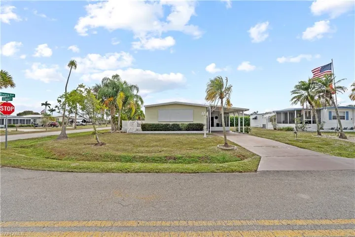 View of front of house with driveway, a front yard, and a carport