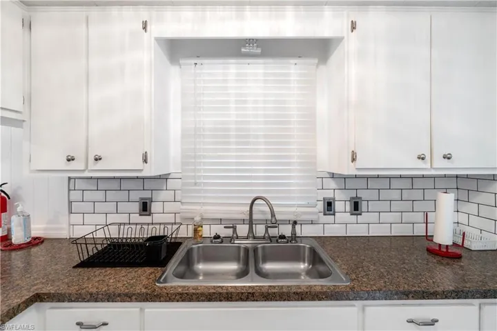 Kitchen featuring tasteful backsplash and white cabinetry