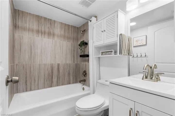 Bathroom with shower / tub combo, toilet, vanity, and visible vents