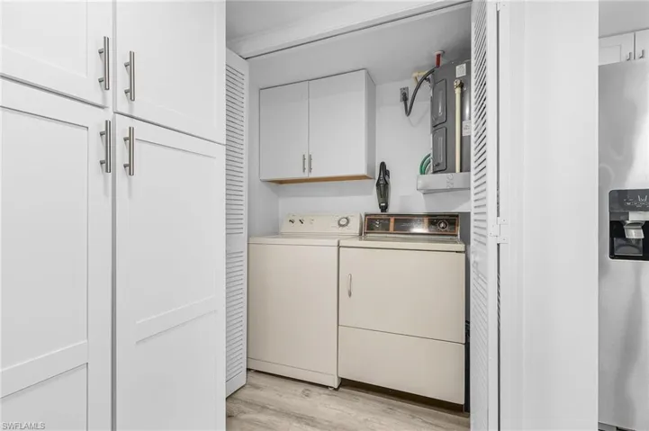 Washroom with separate washer and dryer, cabinet space, and light wood-type flooring