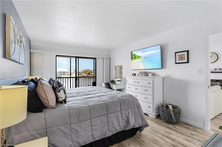 Bedroom with baseboards, access to exterior, and light wood-type flooring