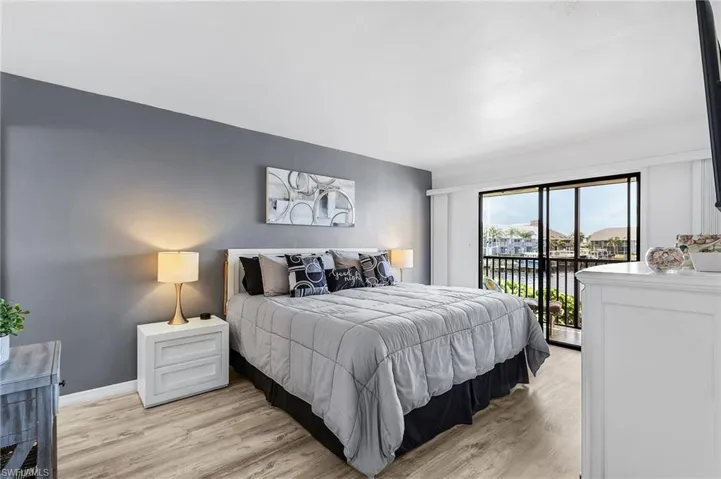 Bedroom with baseboards, access to outside, light wood-style floors, and a water view