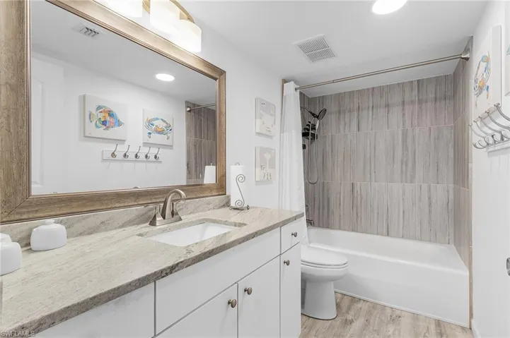 Full bathroom featuring wood finished floors, visible vents, toilet, and vanity