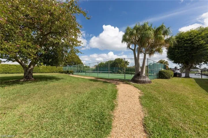 Surrounding community featuring a lawn, a tennis court, and fence