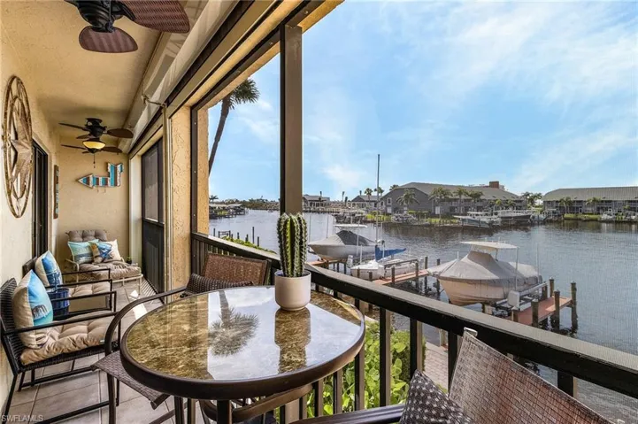 Balcony featuring ceiling fan, a boat dock, boat lift, and a water view