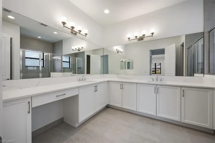 Bathroom featuring tile patterned floors, a shower with shower door, and vanity