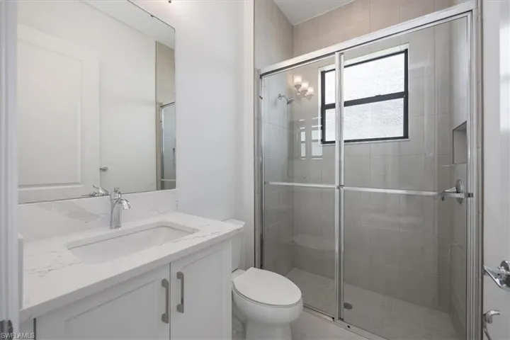 Bathroom with vanity, toilet, and a shower with shower door