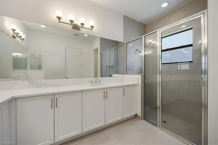 Bathroom with vanity, walk in shower, and tile patterned flooring