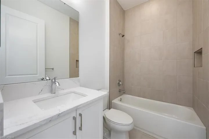 Full bathroom featuring tiled shower / bath combo, vanity, toilet, and tile patterned flooring