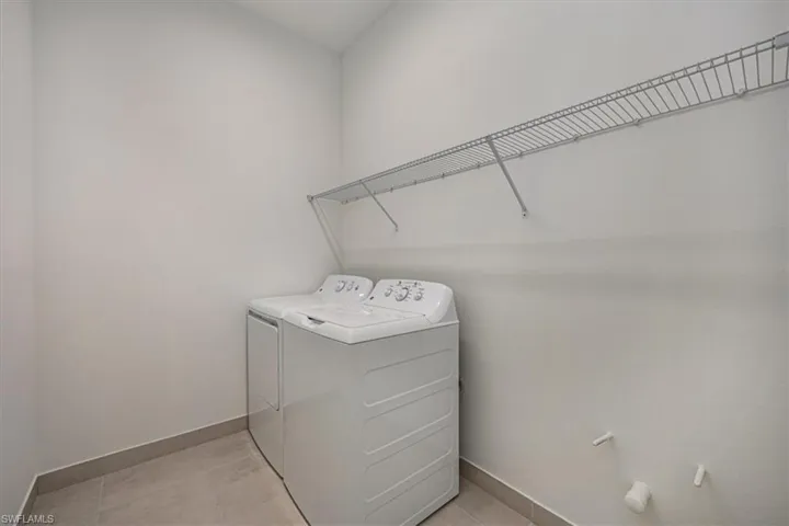 Washroom featuring washing machine and clothes dryer and light tile patterned flooring