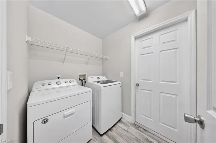 Laundry area featuring wood-finish flooring, a six-panel door, and white wire shelving