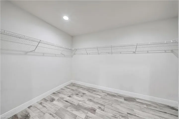 Walk-in closet featuring wood-finish tile flooring, recessed lighting, and wall-mounted wire shelving
