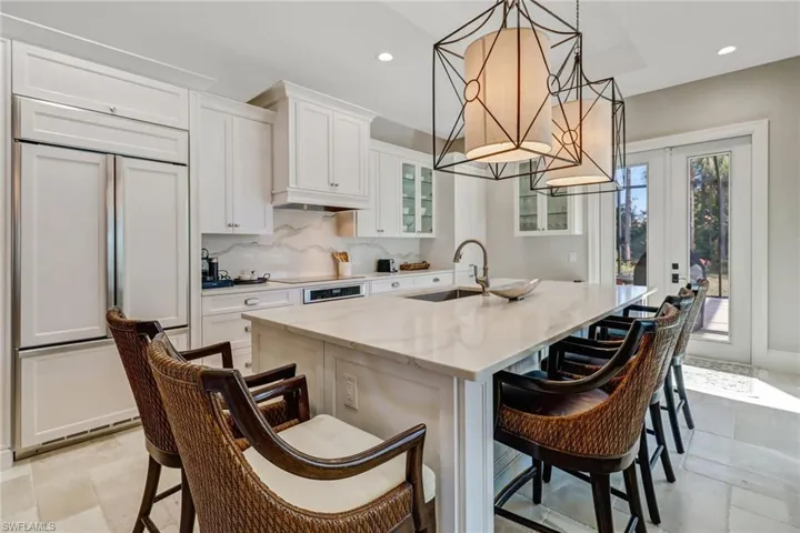 Kitchen featuring a kitchen breakfast bar, paneled fridge, white cabinets, decorative backsplash, and recessed lighting