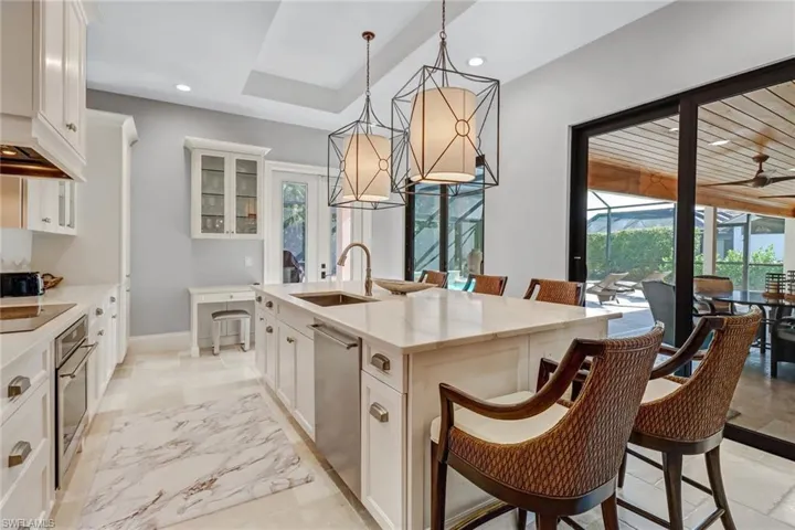 Kitchen featuring a breakfast bar area, white cabinets, glass insert cabinets, light stone counters, and recessed lighting