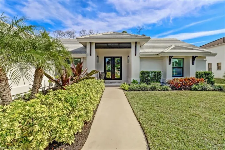 View of exterior entry featuring a tile roof, a yard, french doors, and stucco siding