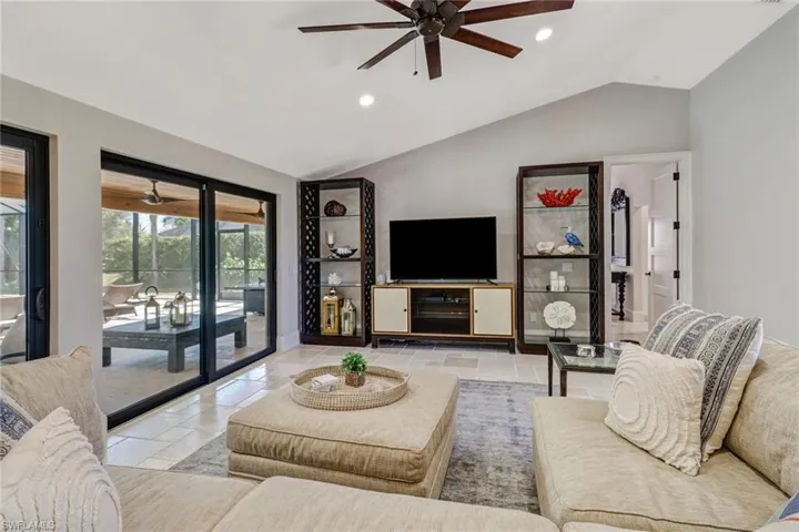 Living room with a ceiling fan, recessed lighting, vaulted ceiling, and stone tile flooring