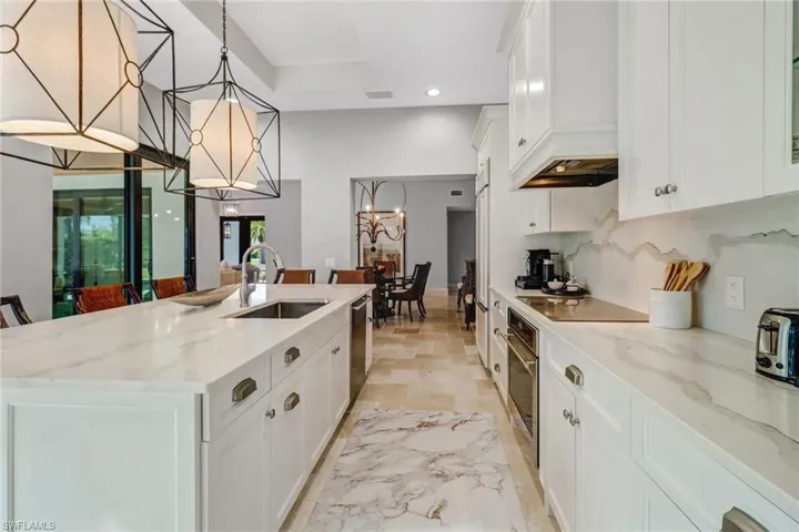 Kitchen featuring white cabinetry, light stone counters, an island with sink, recessed lighting, and stainless steel appliances