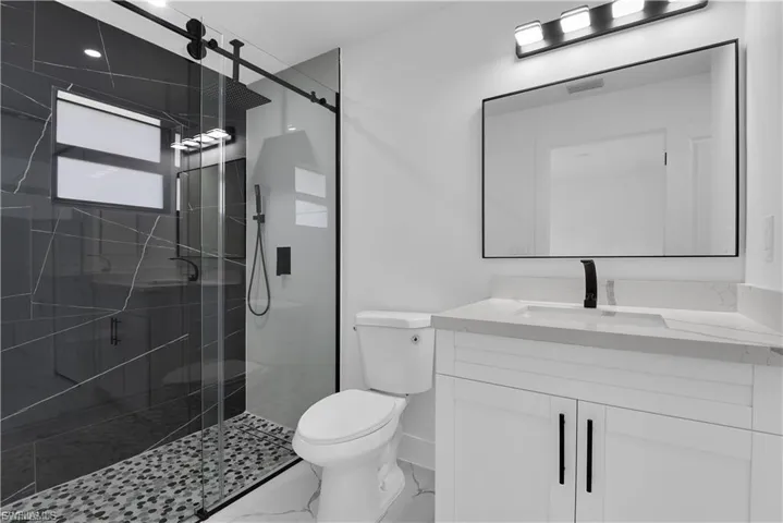 Full bath featuring vanity, a shower stall, and marble look tiles