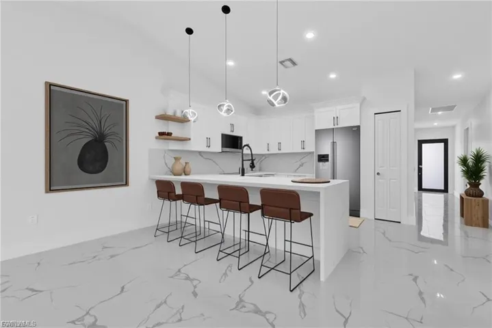 Kitchen featuring a kitchen breakfast bar, white cabinetry, a peninsula, pendant lighting, and stainless steel appliances