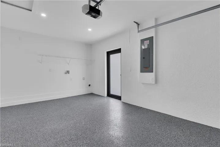 Garage with electric panel, a garage door opener, and recessed lighting