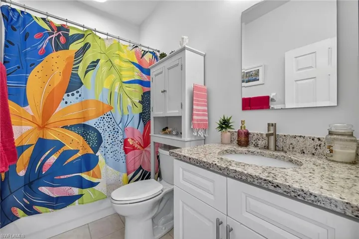 Bathroom with light tile patterned floors, vanity, and shower / bath combo with shower curtain