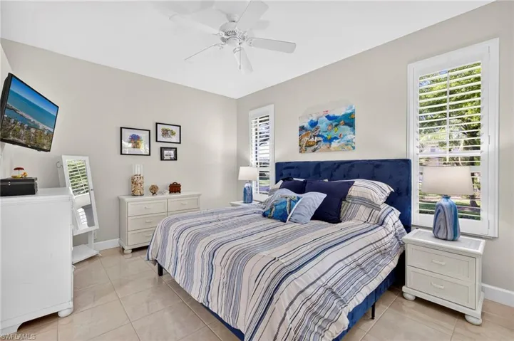 Bedroom featuring multiple windows, light tile patterned flooring, and a ceiling fan