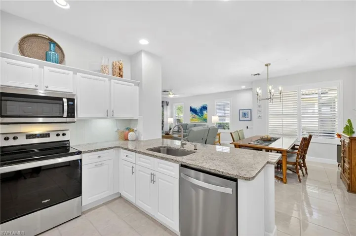 Kitchen with appliances with stainless steel finishes, light stone counters, white cabinetry, tasteful backsplash, and recessed lighting