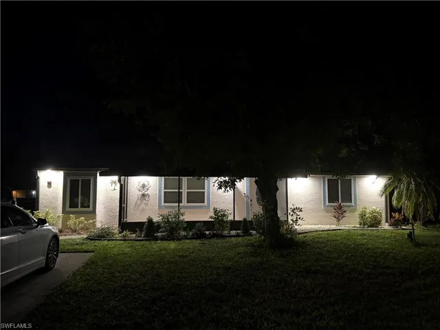 Obstructed view of property with stucco siding and a front lawn