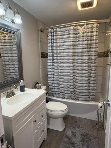 Full bathroom featuring shower / bath combo, dark wood-style flooring, and vanity