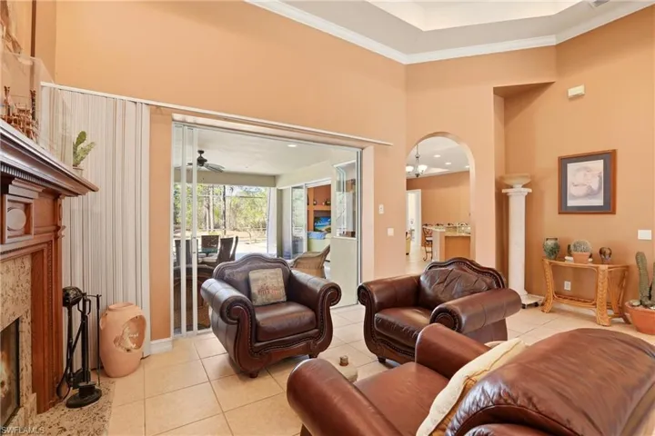Living area featuring a fireplace, ceiling fan, light tile patterned floors, crown molding, and a high ceiling
