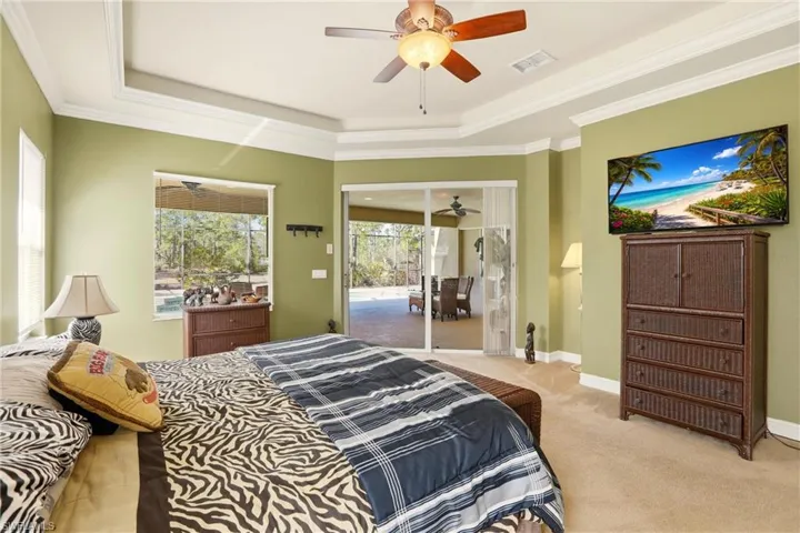 Carpeted bedroom with a tray ceiling, access to outside, crown molding, and ceiling fan