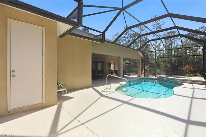 Combined pool / hot tub featuring a patio area, glass enclosure, and a sunroom