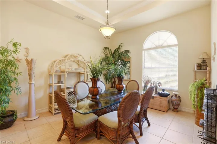 Dining room with tile patterned floors, a raised ceiling, and crown molding