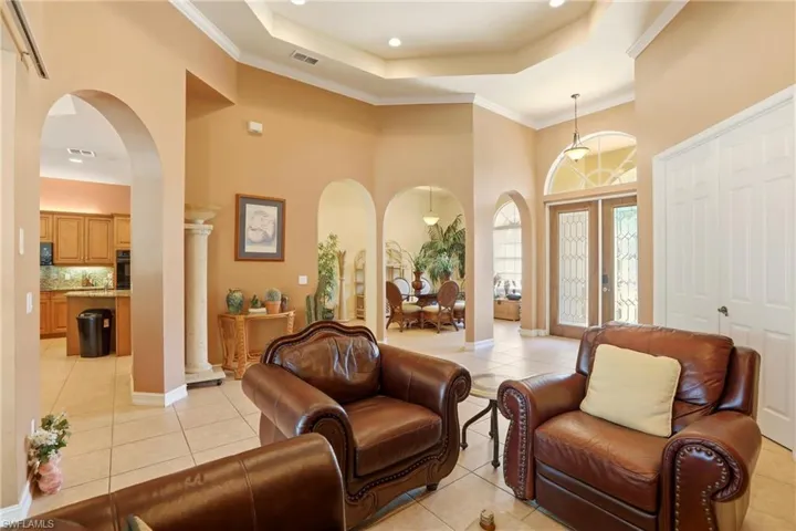 Entrance foyer featuring arched walkways, crown molding, light tile patterned floors, a high tray ceiling, and recessed lighting