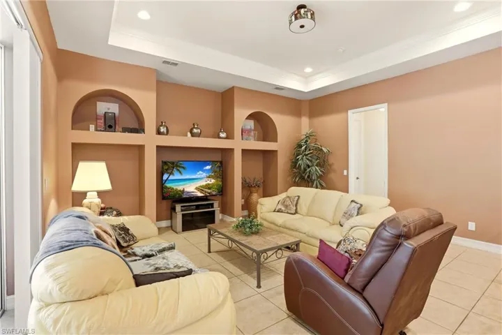 Living area with built in shelves, light tile patterned floors, recessed lighting, a raised ceiling, and ornamental molding