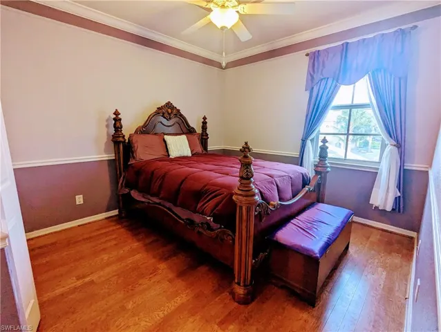 Bedroom featuring ceiling fan, hardwood / wood-style flooring, and crown molding
