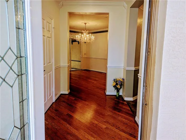 Corridor featuring a notable chandelier, ornamental molding, and hardwood / wood-style floors