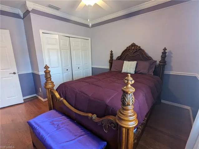 Bedroom with dark hardwood / wood-style floors, ceiling fan, a closet, and crown molding