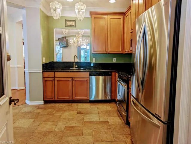 Eat in Kitchen featuring hanging light fixtures, appliances with stainless steel finishes, a chandelier, sink, and light tile floors