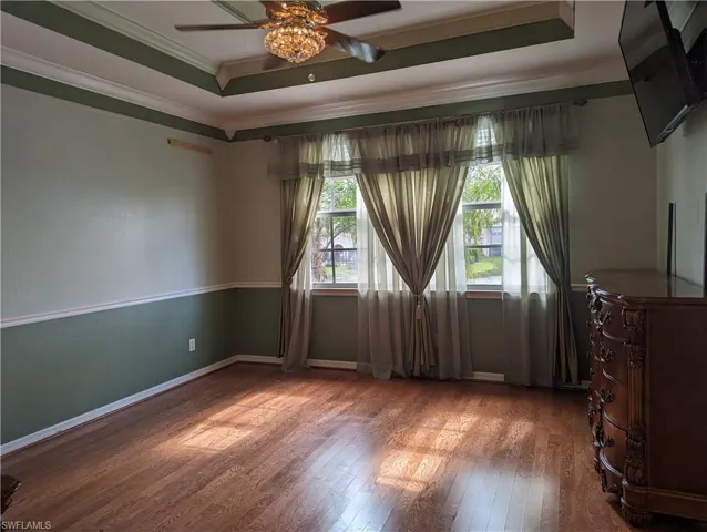 Master Bedroom, wood flooring, ceiling fan, a tray ceiling, and crown molding