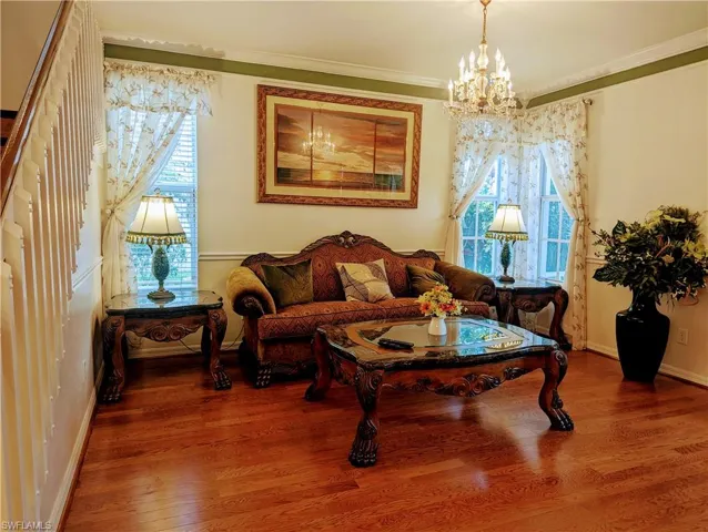 Living room with a notable chandelier, ornamental molding, and hardwood / wood-style floors