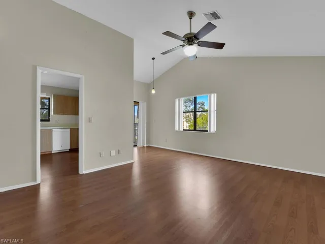 Unfurnished living room featuring ceiling fan, dark hardwood / wood-style flooring, and vaulted ceiling
